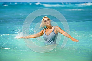 Young happy and sexy blond woman in bikini playing with waves in the sea at stunning beautiful tropical beach enjoying carefree