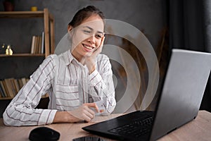 young happy shy hispanic woman watching video online using laptop computer sitting at home desk, student girl has video