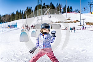 Young happy skier girl throwing snowballs in snowball fight