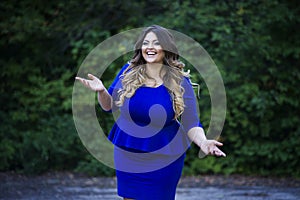 Young happy smiling beautiful plus size model in blue dress outdoors, xxl woman on nature