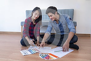 Young happy smiling couple choosing colors for painting their home