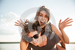 Young happy smiling couple in love piggyback at the beach