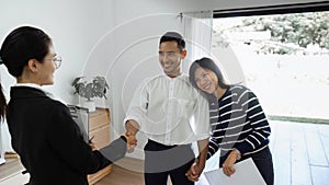 Young happy smiling couple read agreement with realtor and looking through the contract of real estate sale going to