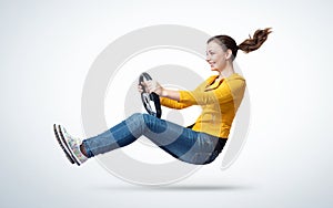 Young happy smiling girl drives a car with steering wheel in hands, auto concept