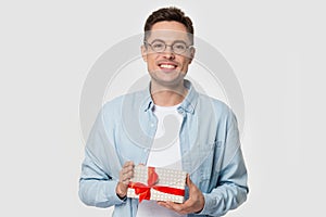 Young happy smiling guy in eyeglasses holding present.