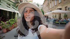 Young happy smiling tourist Indian Arabian lady woman female student waving hand social media vlogger holding smartphone