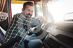 Young and happy smiling truck driver inside his vehicle