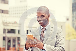 Young happy smiling urban professional man using smart phone outdoors