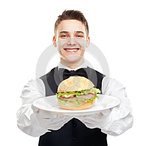 Young happy smiling waiter holding hamburger on plate