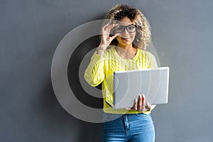 Young happy smiling woman in casual clothes holding laptop and sending email to her best friend.