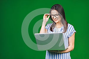 Young happy smiling woman in casual clothes holding laptop and sending email to her best friend