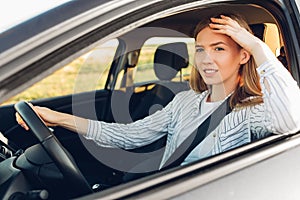 Young happy smiling woman driving her new car at sunset