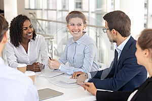 Young happy smiling woman talking to colleague in office.