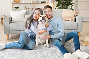Young happy spouses with dog posing at home
