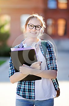 Young happy student girl with books and notes outdoors