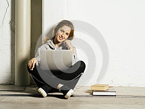 Young happy student working on her laptop in school hallway