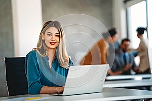 Young happy successful business woman working with laptop in corporate office