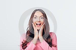 Young happy and surprised woman looking to camera and holds cheeks by hands isolated on white backround