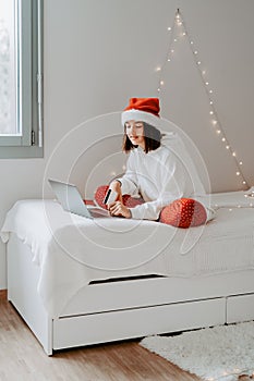 Young happy teen girl in red santa hat shopping online buying Christmas gifts