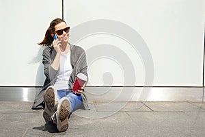 Young happy teen girl using a smart phone over wall in the background