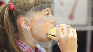 Young happy teenager eating tasty hamburger in fast food restaurant. Teen girl eating french fries for dinner at fast