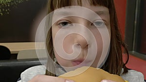 Young happy teenager eating tasty hamburger in fast food restaurant. Teen girl eating french fries for dinner at fast