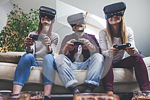 Young happy three friends playing video games virtual reality