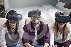 Young happy three friends playing video games virtual reality glasses