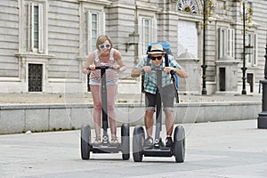 Young happy tourist couple riding segway enjoying city tour in Madrid palace in Spain having fun driving together