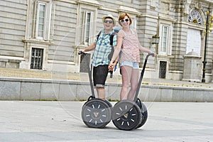 Young happy tourist couple riding segway enjoying city tour in Madrid palace in Spain having fun driving together