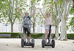 Young happy tourist couple riding segway enjoying city tour in Madrid park in Spain together