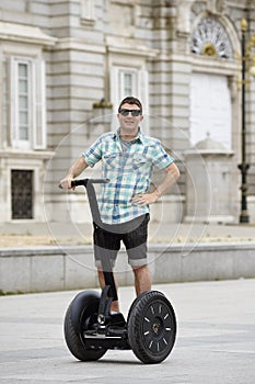 Young happy tourist man riding city tour segway driving happy and excited visiting Madrid palace