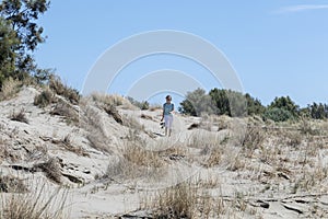 Young happy traveler woman walking on the sand dunes coast of Mediterranean sea, beach Beauduc in French Riviera, France