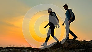 Young Happy Travelers Hiking with Backpacks on the Rocky Trail at Summer Sunset. Family Travel and Adventure Concept.