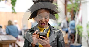 Young happy, trendy and stylish woman using a phone to send a text online in the city. One cheerful, edgy and carefree