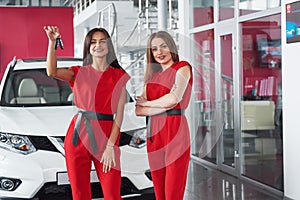 Young happy two woman near the car with keys in hand - concept of buying car