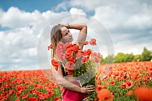 Young happy ukrainian woman holding bouquet of poppies flowers walking, enjoy sunny day in field