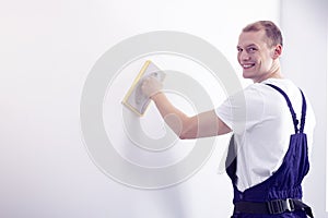 Young, happy wall painter in workwear posing, looking at the cam photo