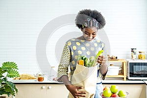 Young happy woman african american afro hair have just returned from the market. and took the tomato, lemon out of the paper bag