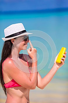 Young happy woman applying suntan lotion on her
