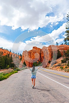 Young happy woman in background of natural stone arch Bridge in the Red Canyon National Park in Utah, USA