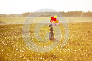 Young happy woman with balloons in a field