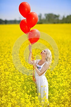 Young happy woman with balloons in a field