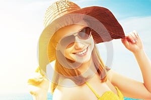 Young happy woman on the beach in sunglasses and a hat