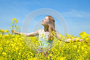 Young happy woman on blooming rapeseed field