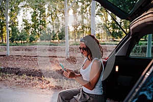 Young happy woman in a car using mobile phone. Travel concept