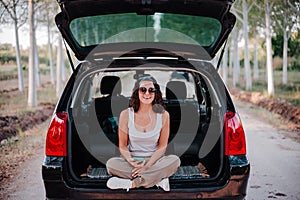 Young happy woman in a car using mobile phone. Travel concept