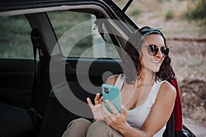 Young happy woman in a car using mobile phone. Travel concept