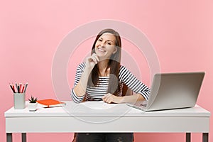 Young happy woman in casual clothes leaning chin on hand sit and work at white desk with contemporary pc laptop isolated