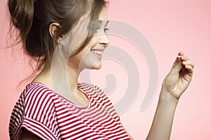 Young happy woman with checking result of a one-time pregnancy test, family planning, motherhood concept on pink studio background